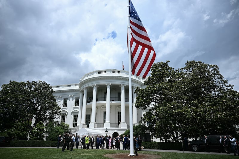 Trump looks on as a U.S. flag is raised on a newly installed flagpole on the South Lawn of the White House.