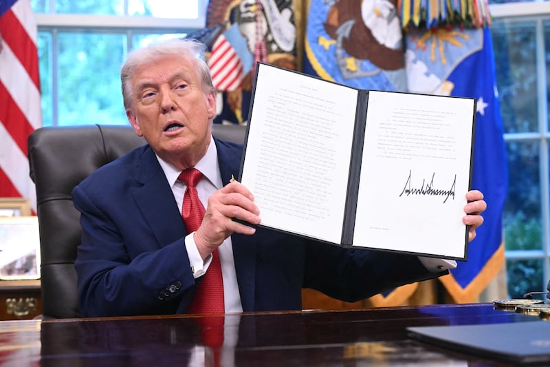 TOPSHOT - US President Donald Trump shows an executive order about Tiktok he signed in the Oval Office of the White House in Washington, DC, on September 25, 2025. The White House has said a US version of TikTok would feature a homegrown model of the app's prized algorithm, potentially clearing one of the main obstacles to keeping the Chinese-owned platform online in the United States. (Photo by SAUL LOEB / AFP) (Photo by SAUL LOEB/AFP via Getty Images)