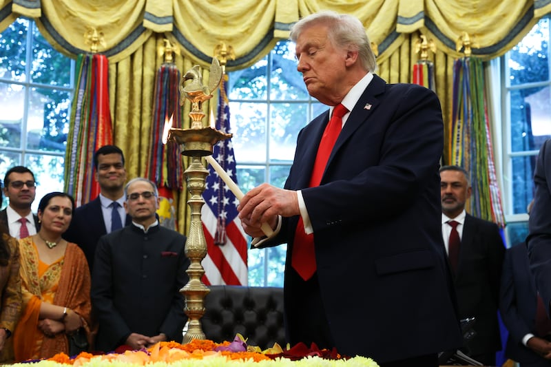 WASHINGTON, DC - OCTOBER 21: U.S. President Donald Trump lights a diya candle during an event celebrating Diwali in the Oval Office of the White House on October 21, 2025 in Washington, DC. Trump held the event to honor the Hindu festival that symbolizes the victory of light over darkness. (Photo by Anna Moneymaker/Getty Images)