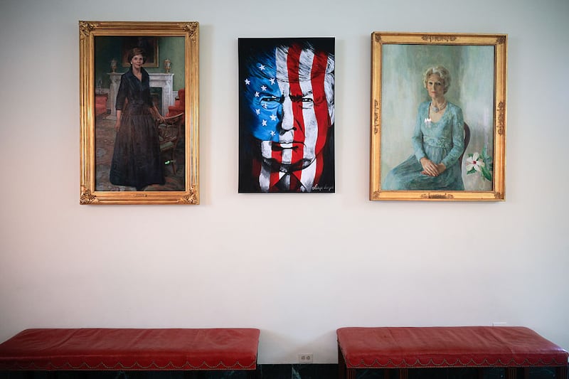 WASHINGTON, DC - JUNE 18: A portrait of President Donald Trump with a U.S. flag on his face is hung between portraits of former first ladies Laura Bush and Patricia Nixon in the East Wing's Visitor Foyer on June 18, 2025 in Washington, DC. Trump hosted a flag-raising ceremony for a new flag pole on the South Lawn and another just like it on the North Lawn, which he said he personally paid for. (Photo by Chip Somodevilla/Getty Images)